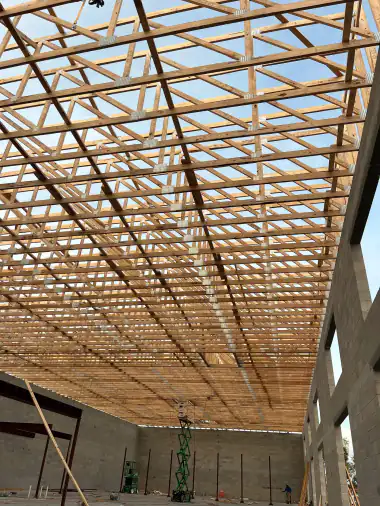 Long-span engineered roof trusses overhead on a Central Florida commercial building, scissor lift below