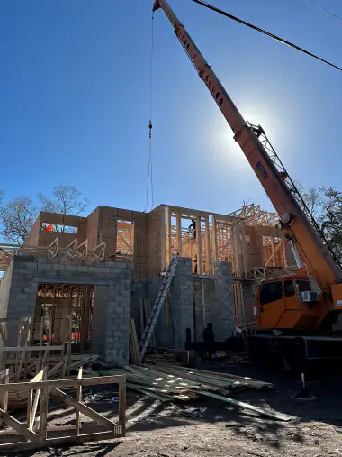 Crane working over braced wood-framed walls on a block base, Central Florida