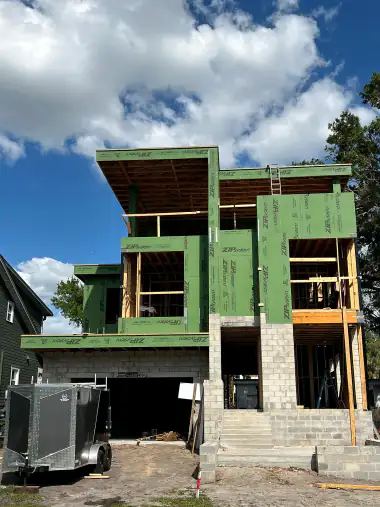 Modern custom home framed with green sheathing and a cantilevered upper floor