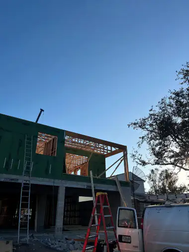 Commercial building shell wrapped in dark sheathing with a ladder set against it
