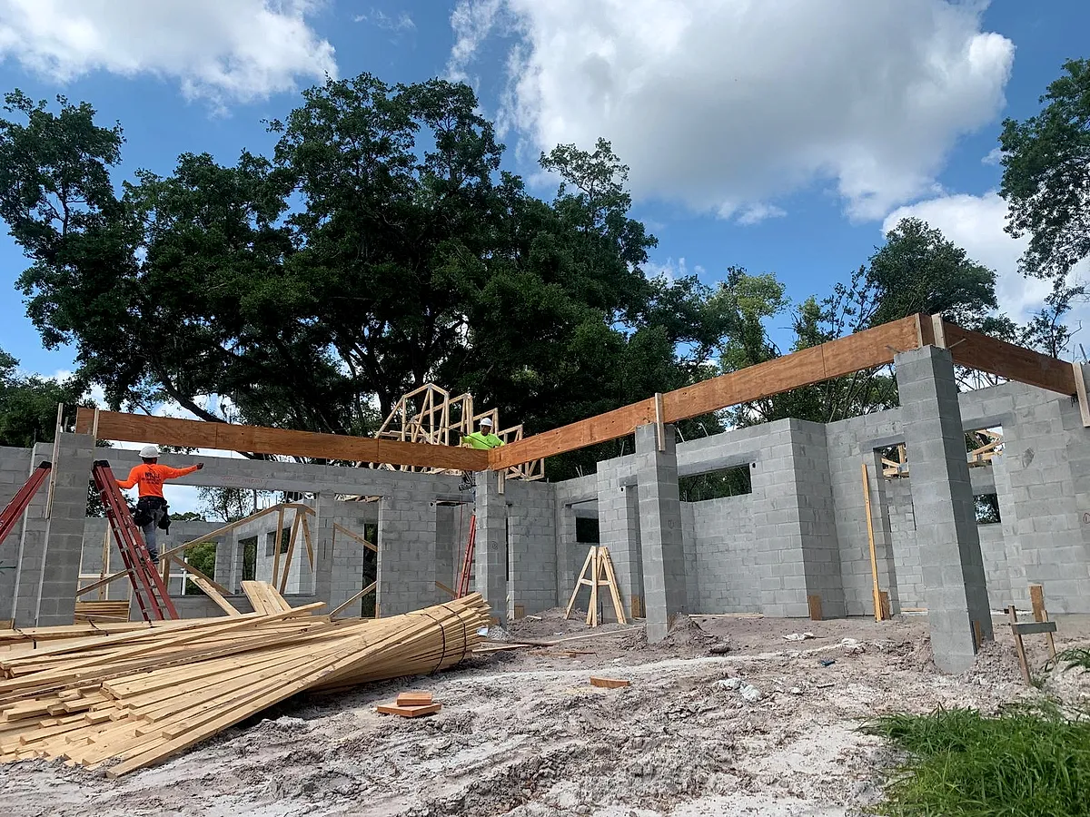 Lumber packages staged against block walls ready for the framing crew
